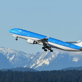 KLM aircraft taking off against snowy mountains