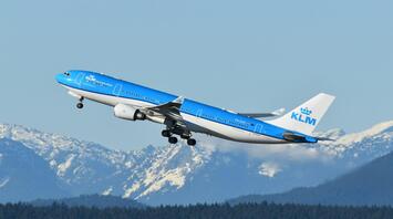 KLM aircraft taking off against snowy mountains