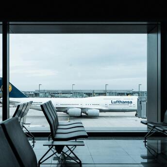 Lufthansa aircraft parked at airport gate viewed from empty terminal seating area