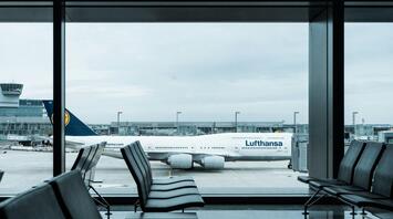 Lufthansa aircraft parked at airport gate viewed from empty terminal seating area