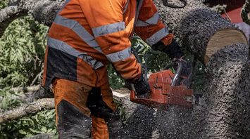 Worker cutting tree branches near railway line