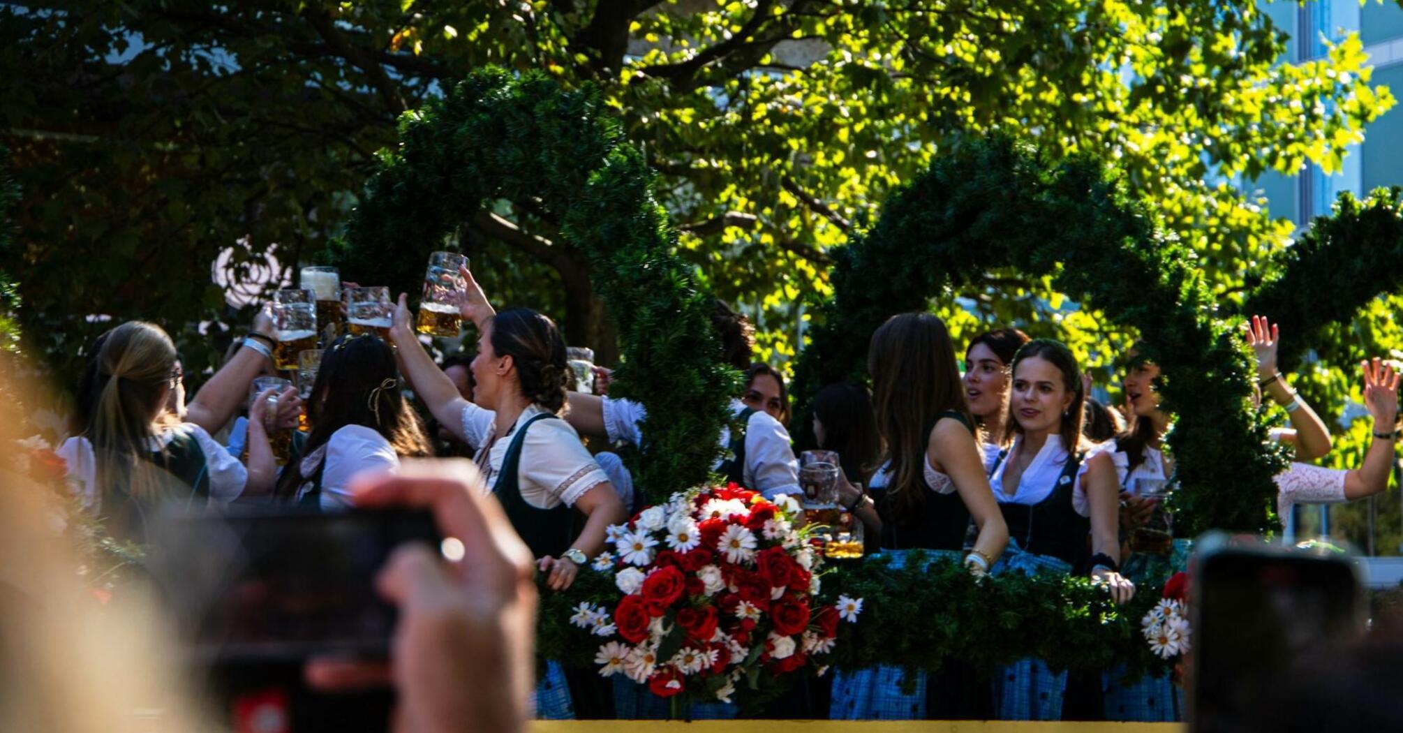 People celebrating with beer mugs at an outdoor Oktoberfest parade float