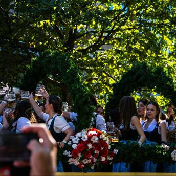 People celebrating with beer mugs at an outdoor Oktoberfest parade float