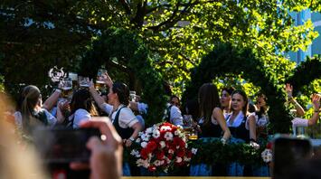 People celebrating with beer mugs at an outdoor Oktoberfest parade float