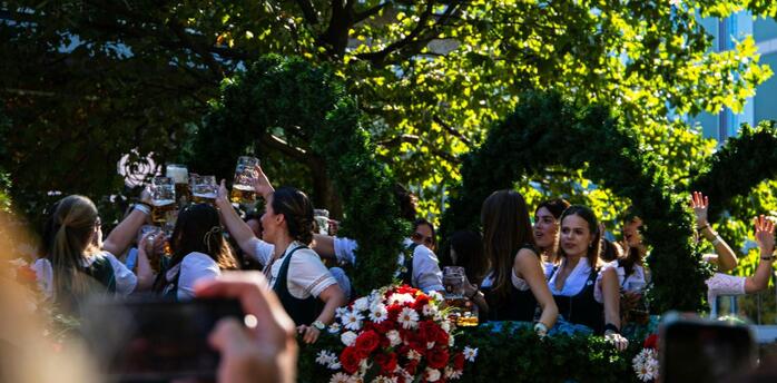 People celebrating with beer mugs at an outdoor Oktoberfest parade float