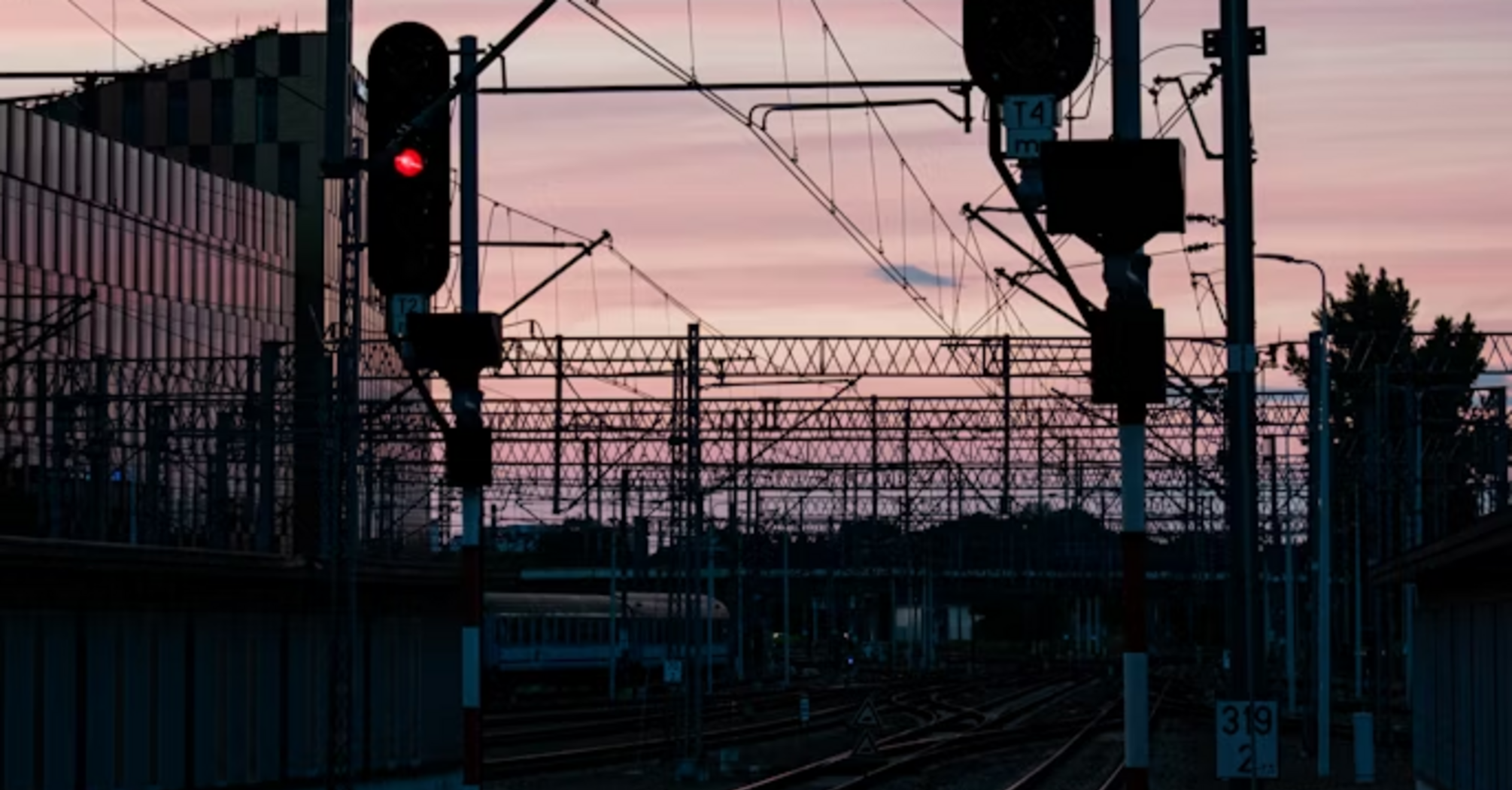 Railway tracks with red signal lights at sunset