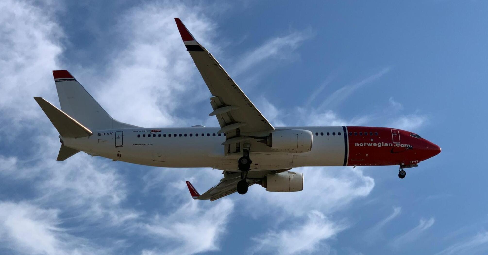 Norwegian aircraft flying against blue sky