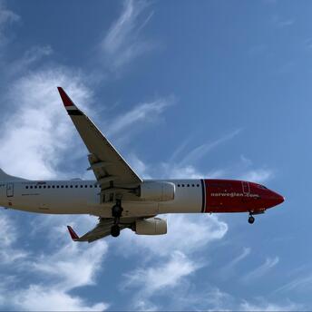 Norwegian aircraft flying against blue sky