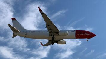 Norwegian aircraft flying against blue sky