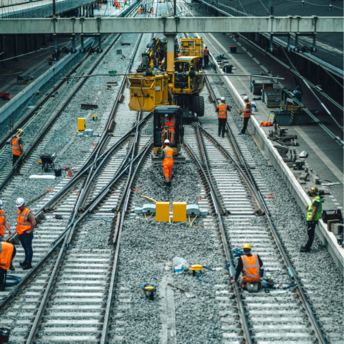 Railway workers maintaining train tracks at a busy station