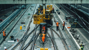 Railway workers maintaining train tracks at a busy station