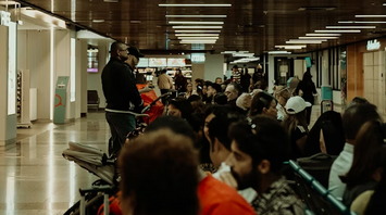 Passengers waiting in a crowded airport terminal with luggage