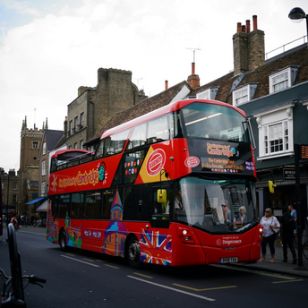 Red double-decker sightseeing bus on a Cambridge street with people nearby