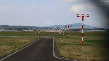 Aircraft landing on a runway with red and white approach lights
