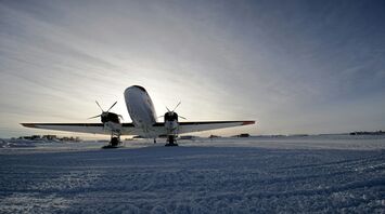 Aircraft parked on snowy runway under winter sky