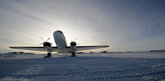 Aircraft parked on snowy runway under winter sky