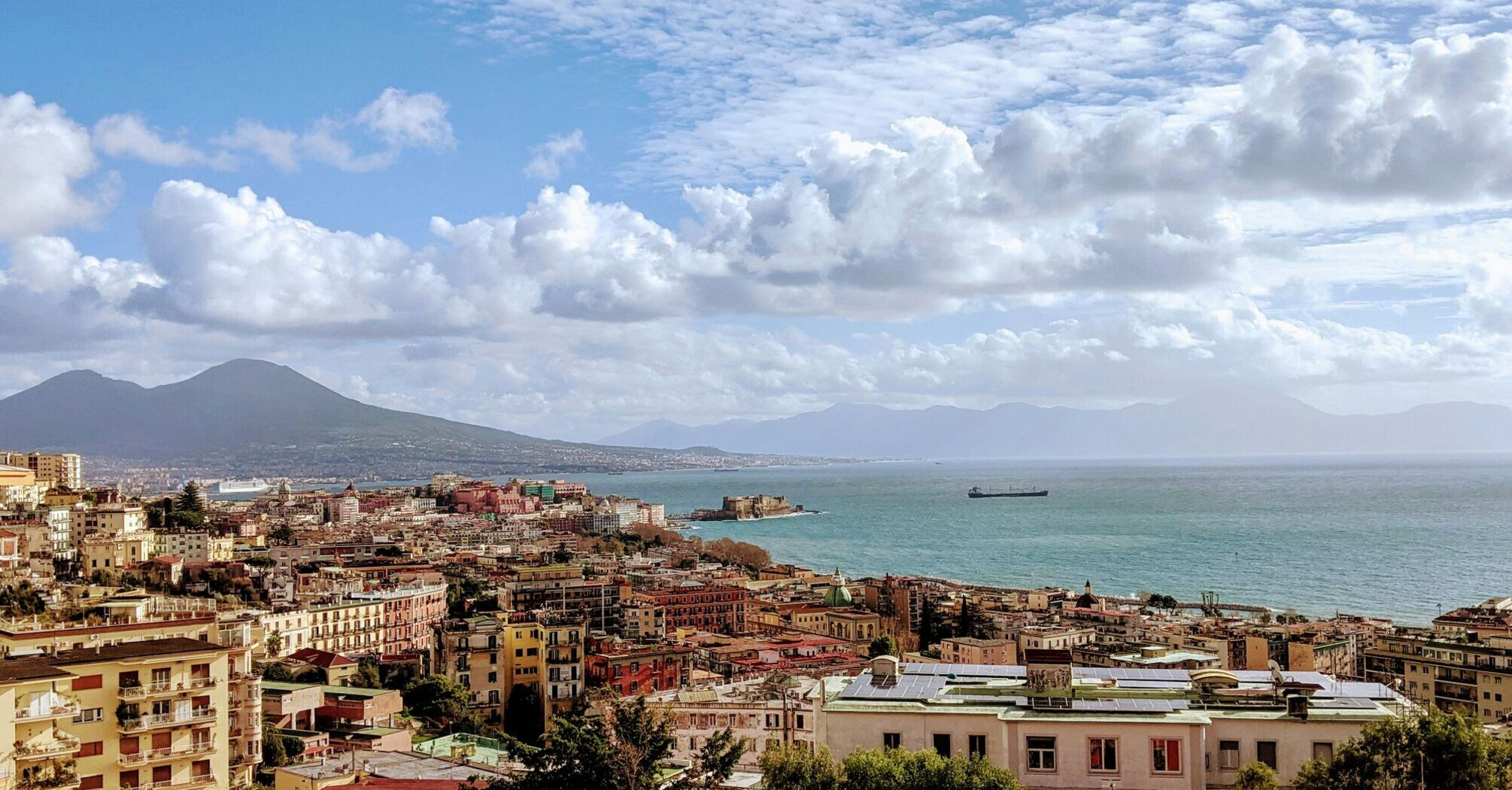 Panoramic view of Naples with Mount Vesuvius and the Gulf of Naples under a partly cloudy sky