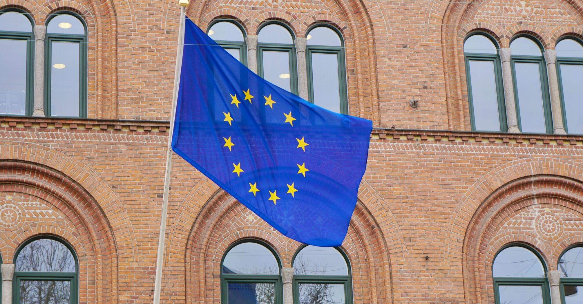EU flag displayed on historic brick building.