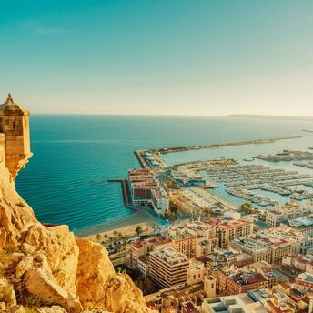 View of Alicante coastline, marina and historic fortress under clear skies