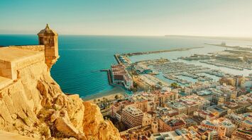 View of Alicante coastline, marina and historic fortress under clear skies