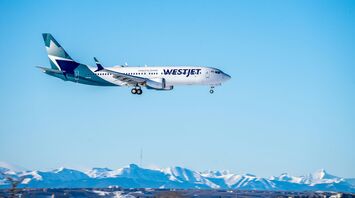 WestJet Boeing aircraft landing with snowy mountains in the background