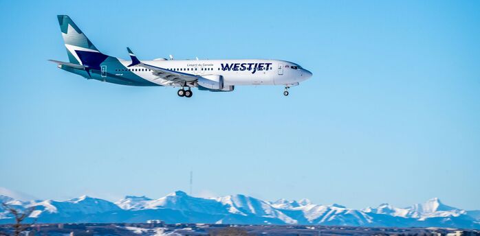 WestJet Boeing aircraft landing with snowy mountains in the background