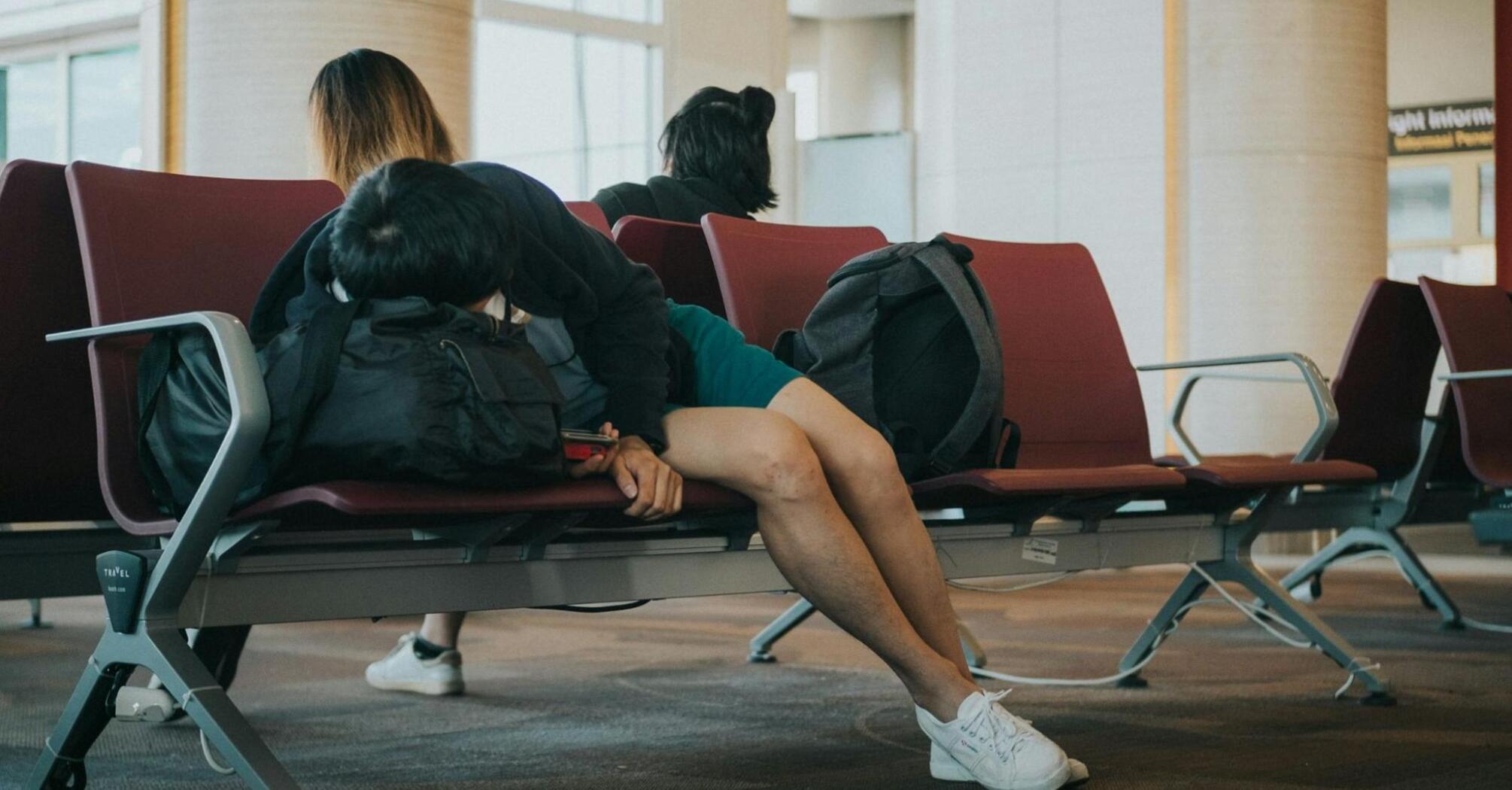 Passengers waiting in airport seating area during flight delays
