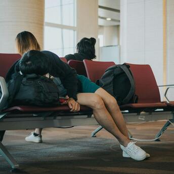 Passengers waiting in airport seating area during flight delays