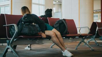 Passengers waiting in airport seating area during flight delays