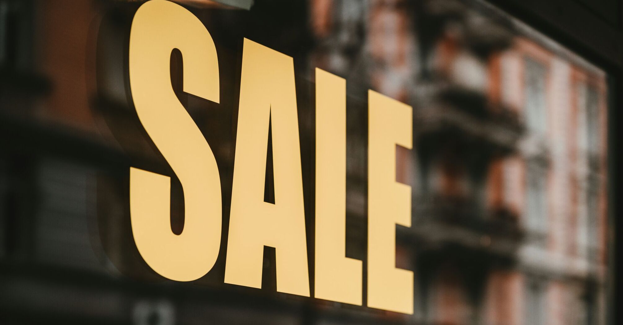 Close-up of a large yellow SALE sign in a shop window