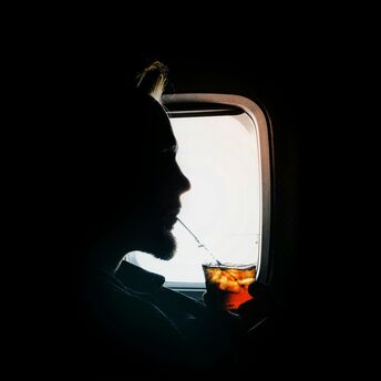 Passenger drinks a cold beverage while seated by an aircraft window