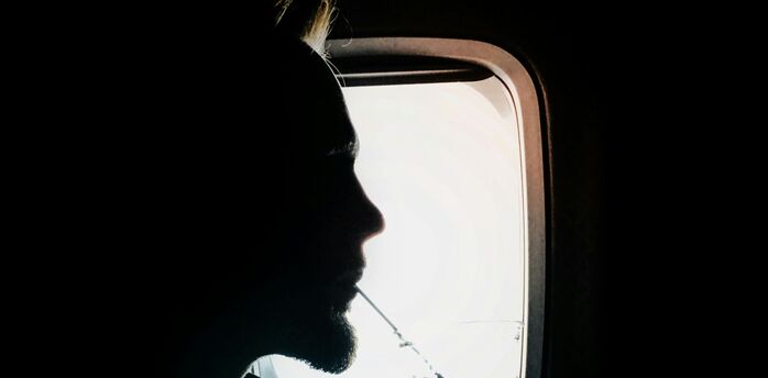 Passenger drinks a cold beverage while seated by an aircraft window