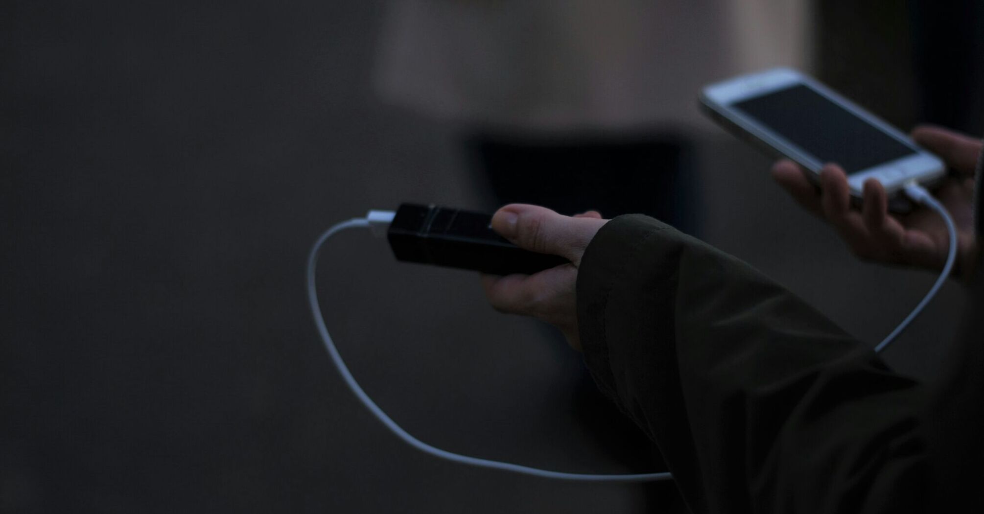 Hand holding a power bank while charging a phone outdoors