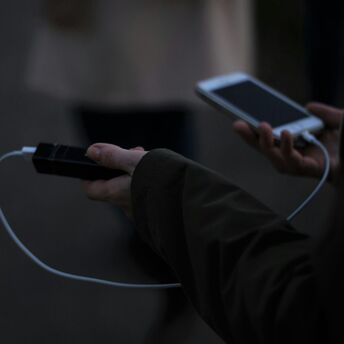 Hand holding a power bank while charging a phone outdoors