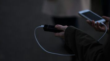 Hand holding a power bank while charging a phone outdoors