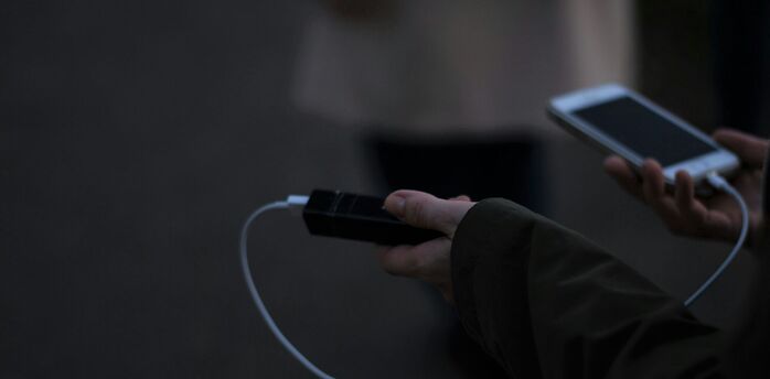 Hand holding a power bank while charging a phone outdoors