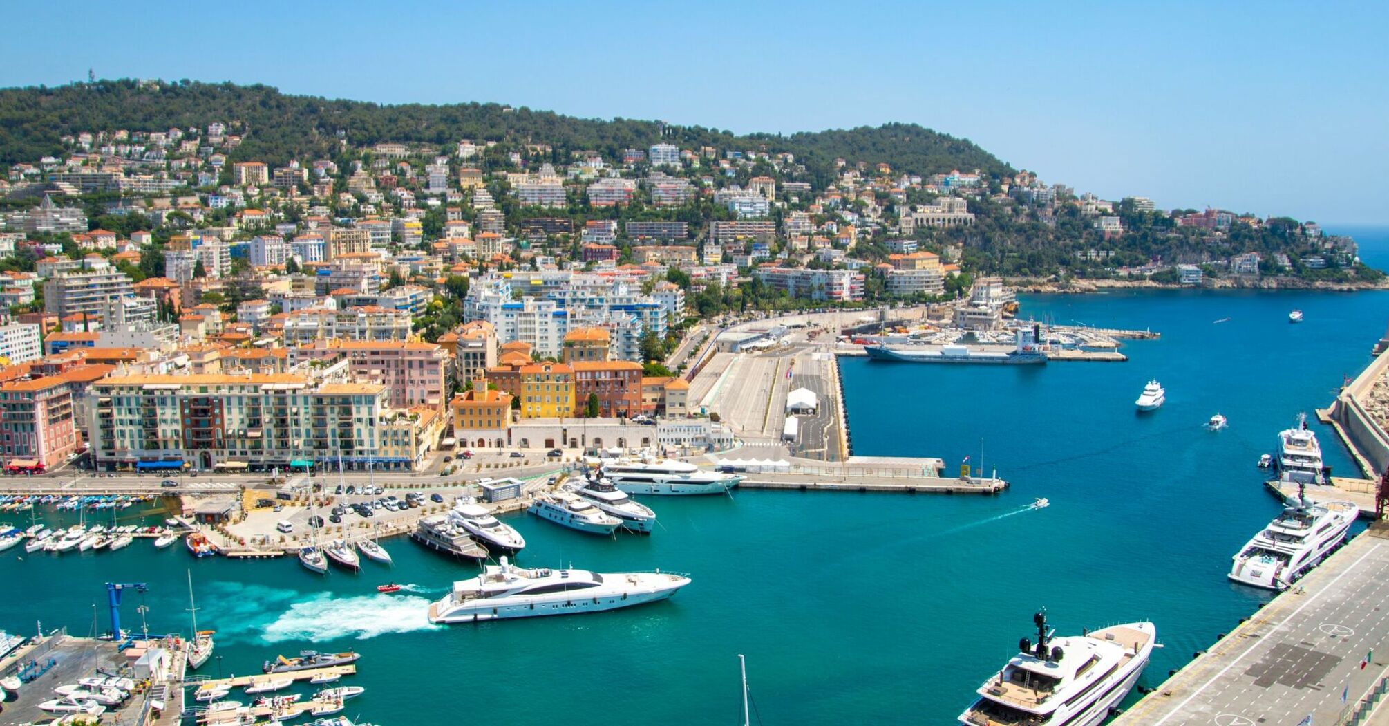 Aerial view of Nice marina with yachts and hillside apartments under a clear sky