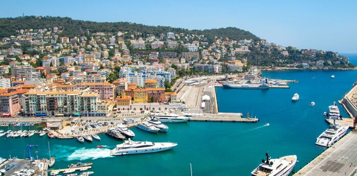 Aerial view of Nice marina with yachts and hillside apartments under a clear sky