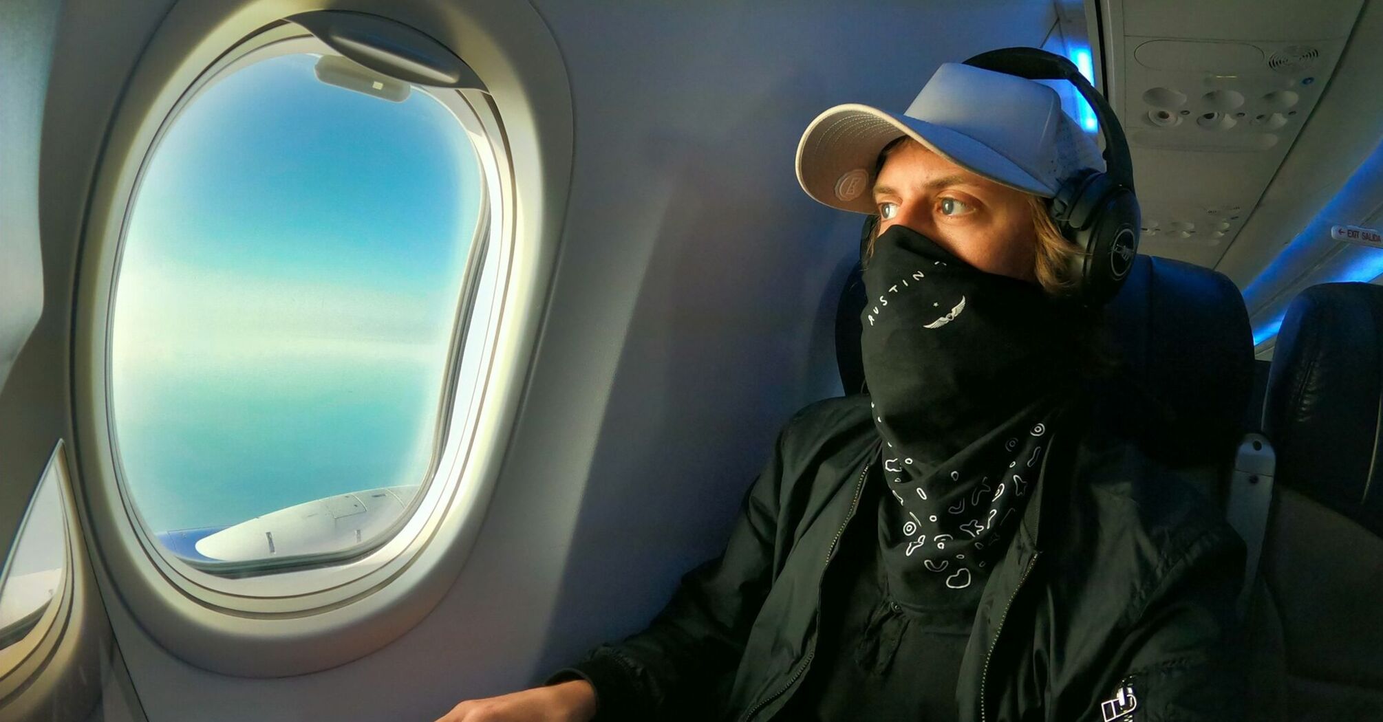 Person using laptop with headphones on an aeroplane