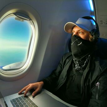 Person using laptop with headphones on an aeroplane