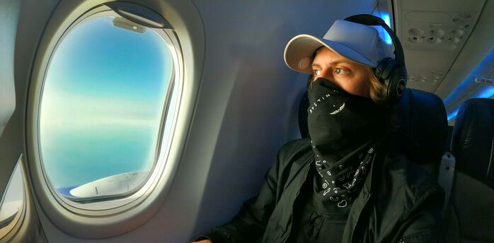 Person using laptop with headphones on an aeroplane