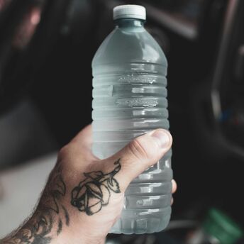 Hand holding a large water bottle inside an airport terminal