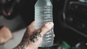 Hand holding a large water bottle inside an airport terminal