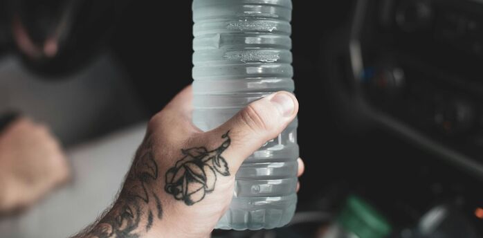 Hand holding a large water bottle inside an airport terminal