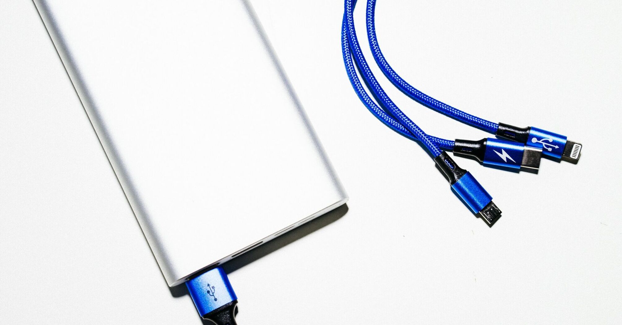 Close-up of a power bank with blue charging cables on a white surface