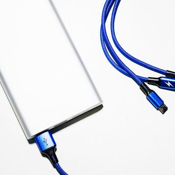 Close-up of a power bank with blue charging cables on a white surface