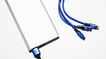 Close-up of a power bank with blue charging cables on a white surface
