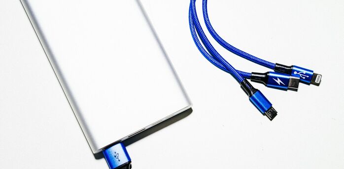 Close-up of a power bank with blue charging cables on a white surface