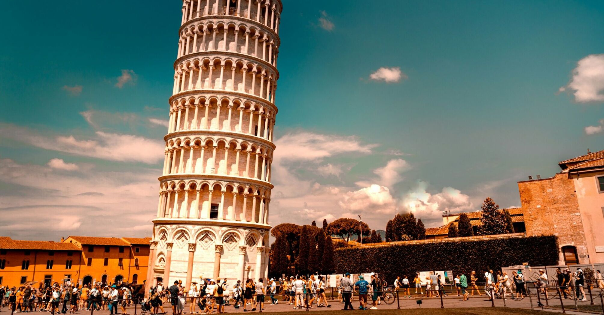 Crowds around the Leaning Tower of Pisa under a bright sky