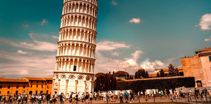 Crowds around the Leaning Tower of Pisa under a bright sky
